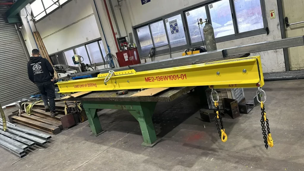 Yellow lifting beam with a rated-load label at the Damti Brothers plant